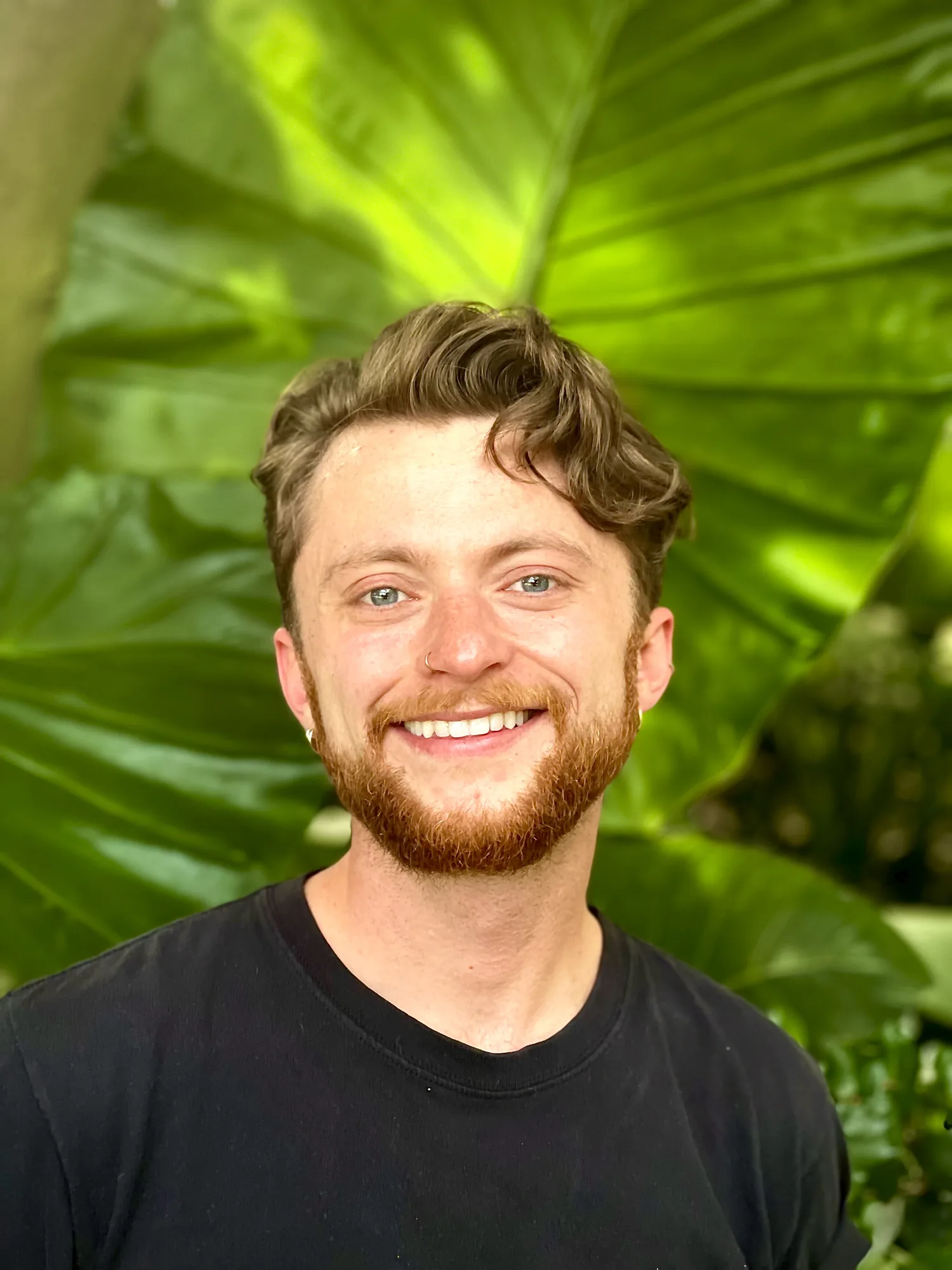 Graham Ivy smiling in front of large green leaves